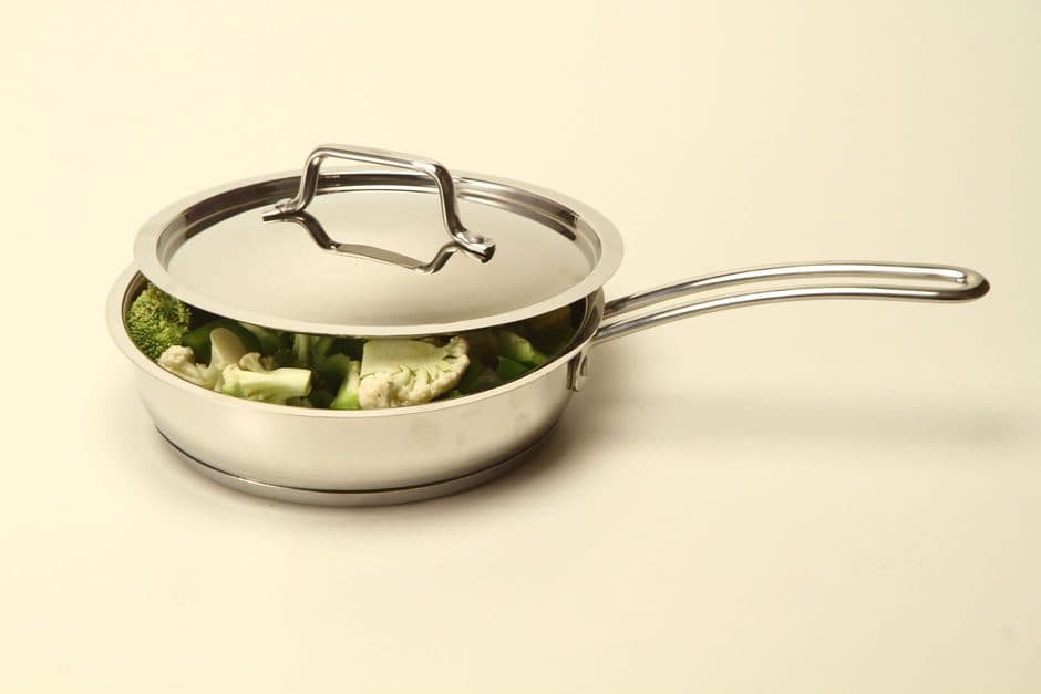 A close view of a polished stainless steel pan and its riveted handle.