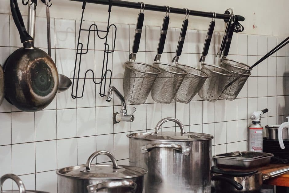 Pots and pans hanging above a kitchen workbench.