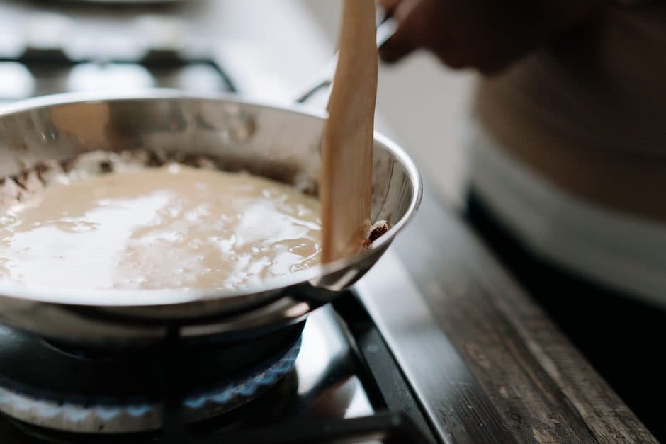 A sauce being stirred in a stainless steel pan.