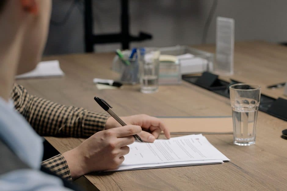 A document being signed with a pen on a table.